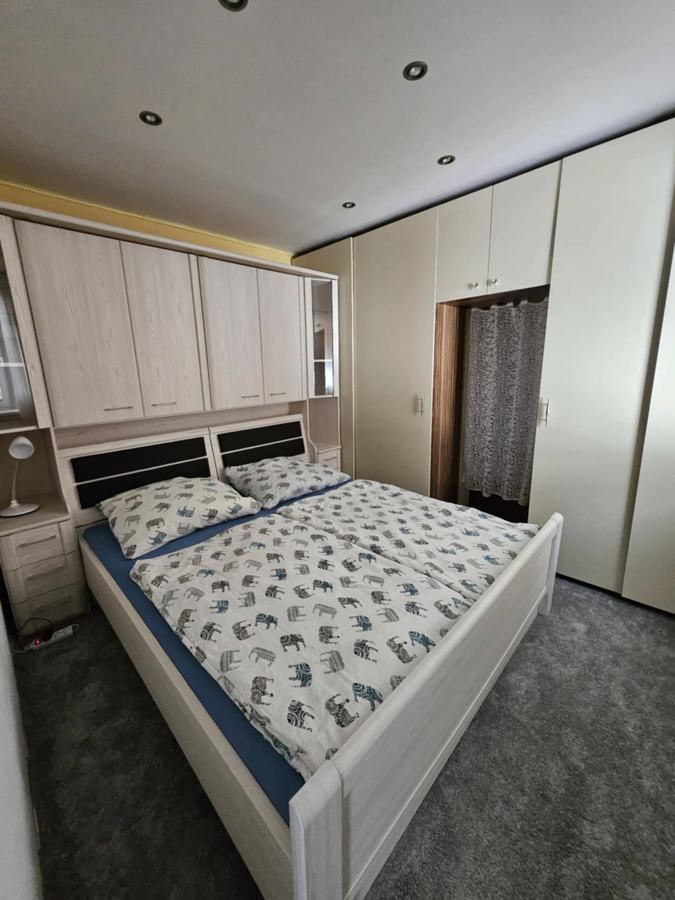Ložnice s manželskou postelí a vestavěnými skříněmi nad hlavou